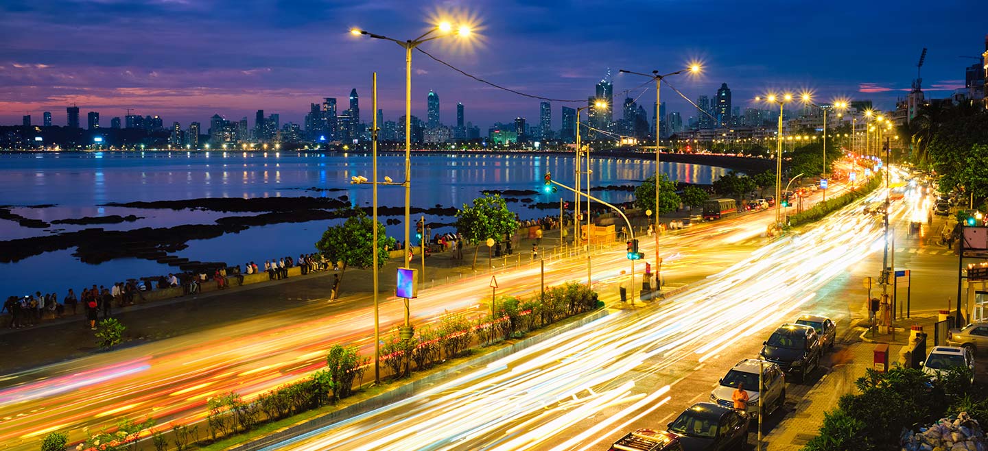 A bustling city street at night, illuminated by the glow of car lights and street lamps